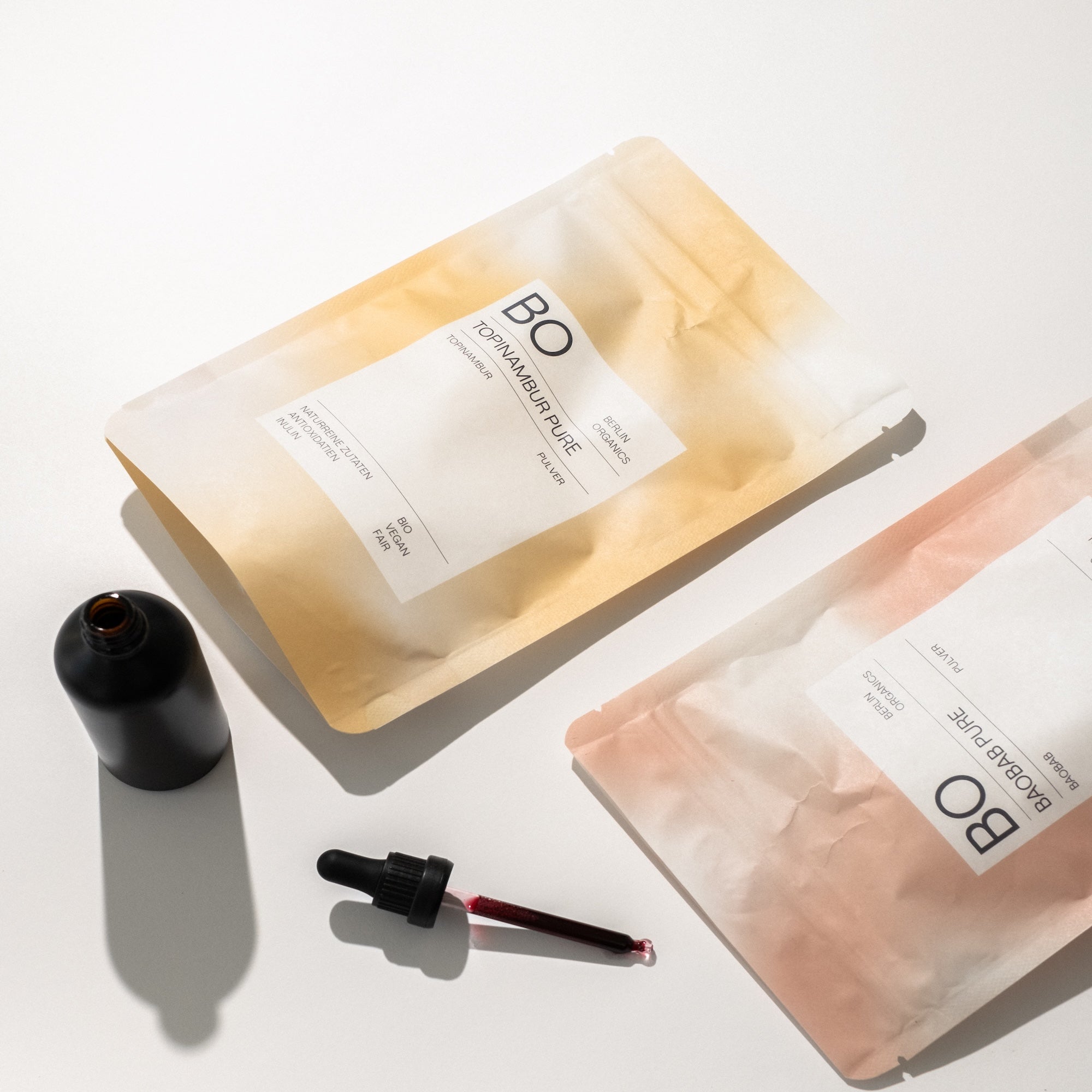 Berlin Organics Verpackungen „Topinambur Pure“ und „Baobab Pure“ mit Pipette und Glasflasche.